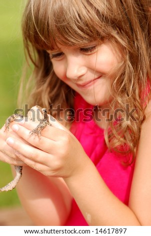 A cute young girl holding a toad