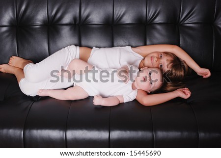 A brother and sister lying on a couch together