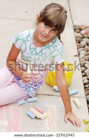 A cute young girl drawing on the sidewalk
