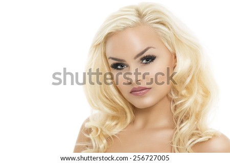 Pretty blond woman with bare shoulders and gorgeous wavy long hair glancing sideways at the camera with a serious thoughtful expression, isolated on white