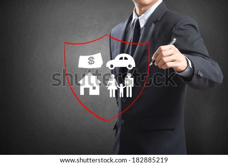 Business man drawing shield protecting family, house, car money.  insurance concept