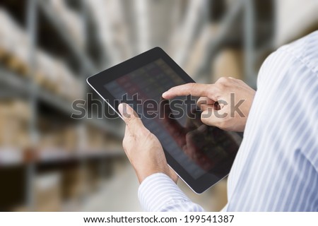 Businessman checking inventory in stock room of a manufacturing company on touchscreen tablet