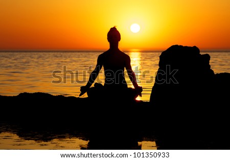 Woman making yoga figure on the beach at sunset