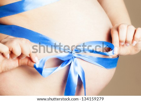Pregnant woman tummy with blue ribbon