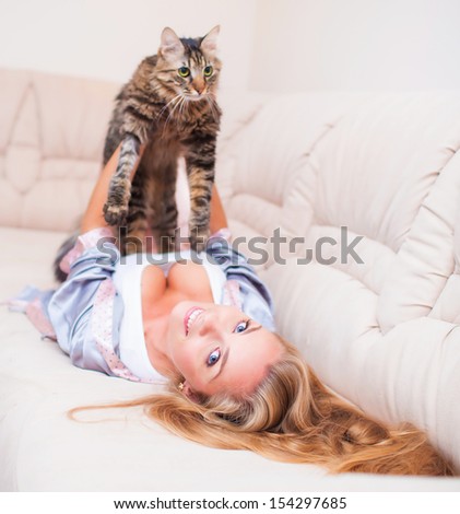 Beautiful young woman at home playing with cat