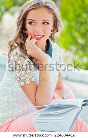 Young beautiful girl reading book in the garden