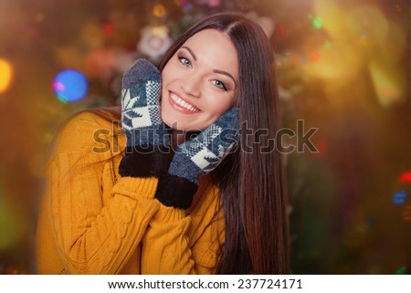 Beautiful young woman in winter clothes near christmas tree