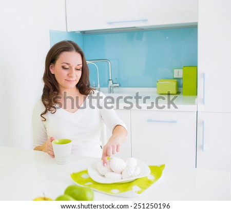 Young beautiful woman eating sweet cake on the kitchen at home