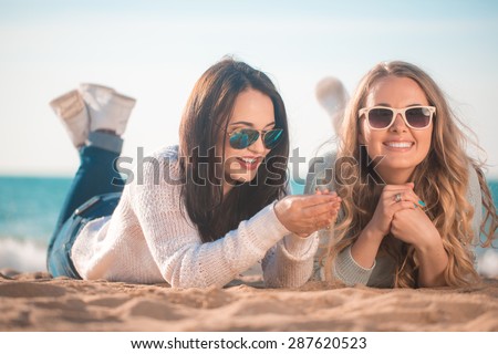 Two girls resting on the autumn beach
