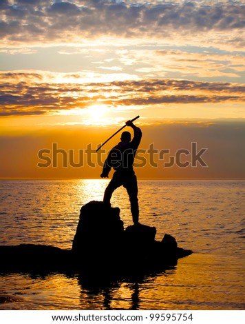 Man with sword near the sea at sunset time