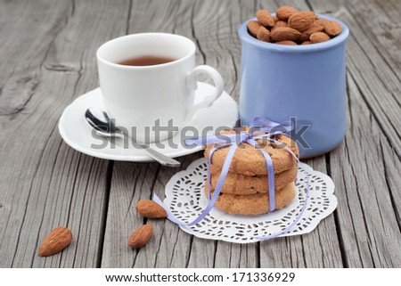 Festive wrapped chocolate homemade cookies and almond with cup of tea on wooden background
