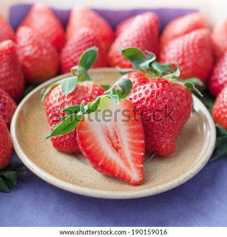 Small plate filled with succulent juicy fresh ripe red strawberries on table
