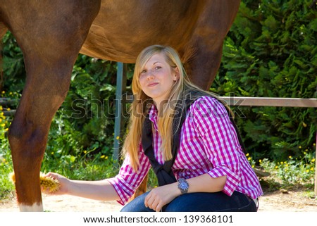 Young woman cleaning her horse