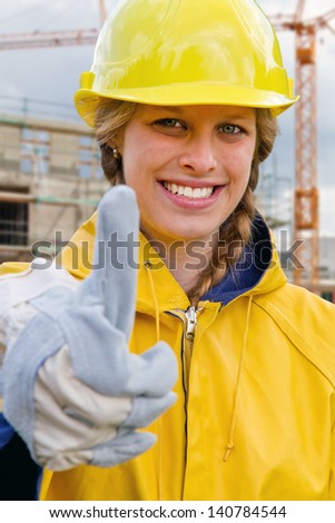 Young woman in work wear with thumb up