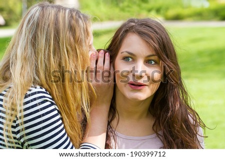 Two young girls whispering to the latest news