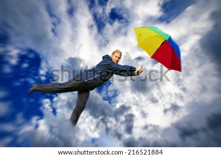Young woman flying with umbrella in the sky