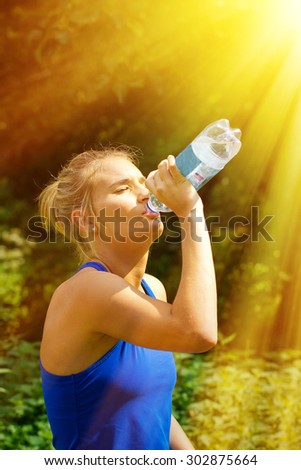 Young woman drinking water on a hot, sunny day