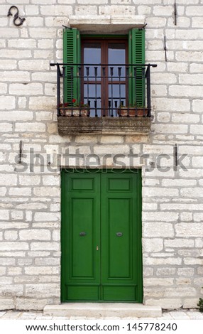 Closed door, window with open green shutters.