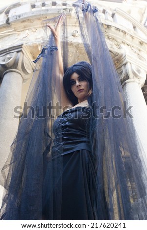 Mysterious woman dressed in black gothic dress.