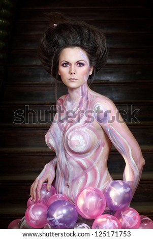 Indoor shoot with young caucasian woman posing in fantasy style dressed to pink body  art and air balloon skirt