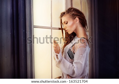 Young and beautiful woman is touching a glowing in the dark window
