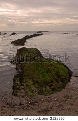Rocks lead out to sunset after storm over Scottish coast