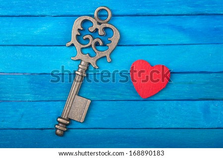 Old key and red heart on a blue wooden background