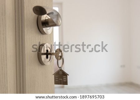 Open door to a new home. Door handle with key and home shaped keychain. Mortgage, investment, real estate, property and new home concept Foto stock © 
