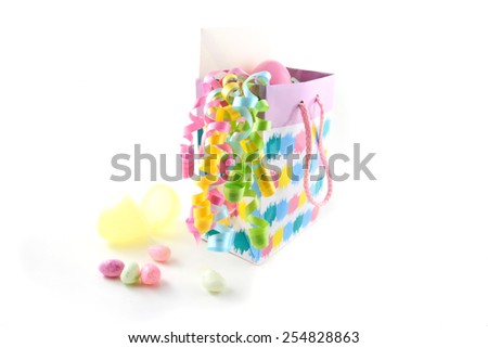 Easter gift bag with candy, gift card, and easter eggs over a white background.