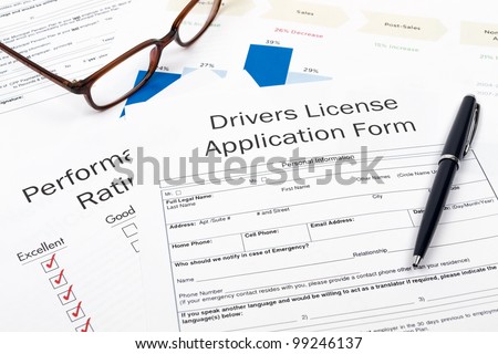 Pen, Glasses and Drivers License Application Form on desktop in business office.