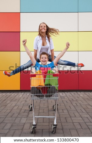 boy and girl  with shopping trolley full of purchases in the street