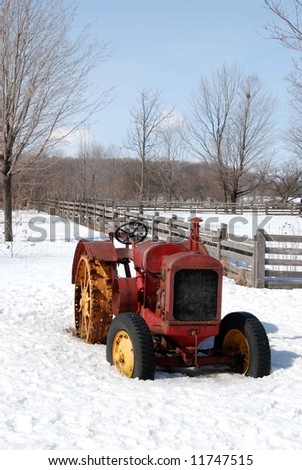 A vintage tractor sitting in a snowy field