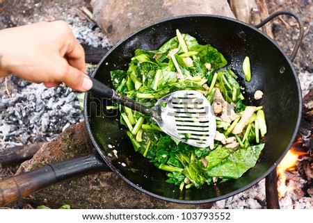 Cooking vegetables and  meat in wok pan at camp