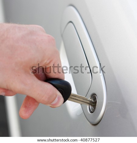 A hand opening a car door with a key