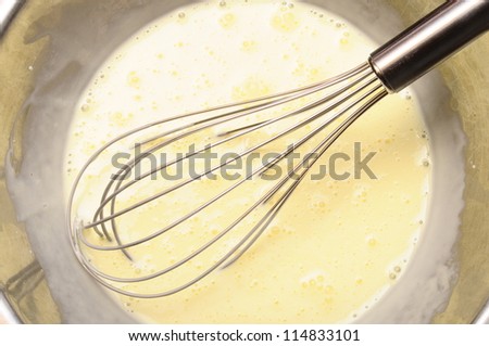 Manual whisk mixing cream and egg for cooking dessert