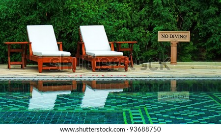 Wooden lawn chairs in a luxury hotel swimming pool, India