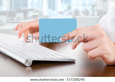 Female hands typing on white computer keyboard in office and give bank card