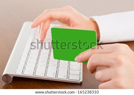 Female hands typing on white computer keyboard in office and give bank card