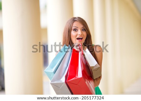 stunning and very beautiful woman in dress with long brown hair with colored shopping bags