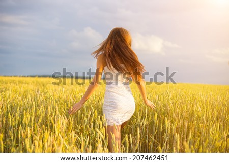 beautiful woman run away in yellow wheat field