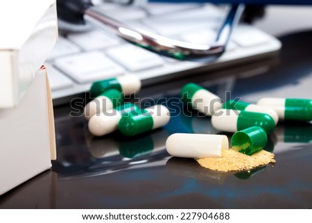 close-up green, white open medical capsules, (one opened), on black background