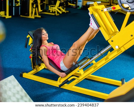 Side view of a fit young woman doing leg presses in the gym