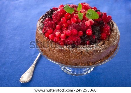 Wild fresh berry fruits chocolate cake on blue.