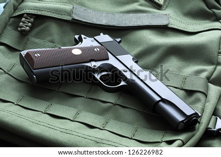 Legendary semi-automatic M1911 Mark IV Series 80 .45 caliber pistol on a green background with the \