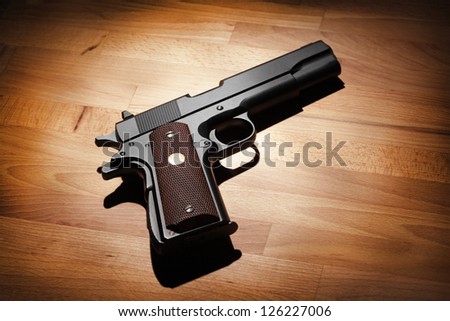 M1911 semi-automatic .45 caliber pistol on a wooden surface. Studio shot