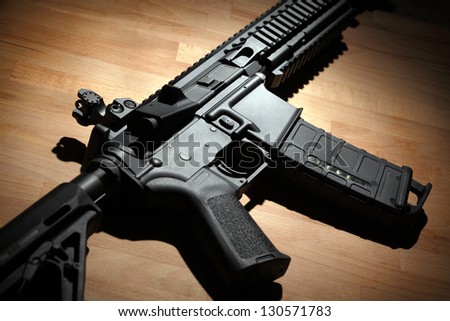 Modern custom AR-15 (M4A1) carbine on a wooden surface. Studio shot