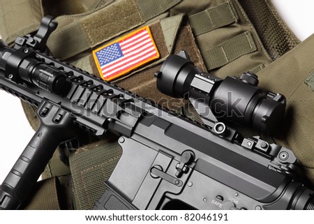 Military concept. Green tactical body armor with U.S. stripe flag and M4A1 assault rifle close-up. Studio shot.