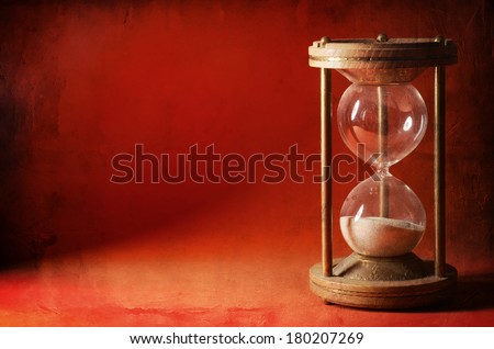 time concept with hourglass lying toned in warm orange and red colors, ancient sandglass