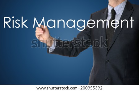 businessman writing risk management on blue background