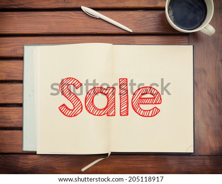 Notebook with text Sale inside on table with coffee